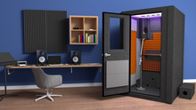 Load image into Gallery viewer, Immaculate WhisperRoom's Voice Over Basic Package - a 4' x 4' single-wall vocal booth adorned with striking orange acoustic treatment, a sleek desk, studio lighting, and an array of features. Set within a cozy home studio, it features a condenser microphone, creating an inviting and professional recording space.