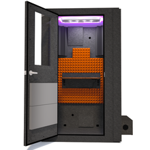 Load image into Gallery viewer, Front view of WhisperRoom's Voice Over Basic Package - a 4' x 4' single-wall vocal booth, thoughtfully furnished with acoustic treatment, a functional desk, studio lighting, and a comprehensive range of premium features. The left-hinged door is open, revealing the interior accented with vibrant orange StudioFoam, creating an ideal recording atmosphere.