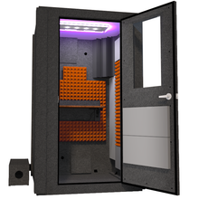 Load image into Gallery viewer, Angled view of the WhisperRoom's Voice Over Basic Package - a 4' x 4' single-wall vocal booth, expertly equipped with acoustic treatment, a functional desk, studio lighting, and an array of premium features. The right-hinged door is open, revealing the interior enhanced by vibrant orange StudioFoam, creating an ideal recording atmosphere.