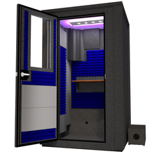 Load image into Gallery viewer, Angled view of the WhisperRoom's Voice Over Deluxe Package - a 4' x 4' double-wall vocal booth, thoughtfully equipped with acoustic treatment, a functional desk, studio lighting, and a comprehensive range of premium features. The left-hinged door is open, revealing the interior accentuated with vibrant blue StudioFoam, creating an ideal recording atmosphere.