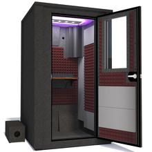 Load image into Gallery viewer, Angled view of WhisperRoom's Voice Over Deluxe Package - a 4' x 4' double-wall vocal booth, meticulously designed with acoustic treatment, a functional desk, studio lighting, and a comprehensive range of premium features. The right-hinged door is open, revealing the interior enhanced by sophisticated burgundy StudioFoam, creating an ideal recording atmosphere.