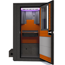 Load image into Gallery viewer, Frontal view of the WhisperRoom's Voice Over Deluxe Package - a 4' x 4' double-wall vocal booth, thoughtfully equipped with acoustic treatment, a functional desk, studio lighting, and a comprehensive range of premium features. The right-hinged door is open, revealing the interior enhanced by vibrant orange StudioFoam, creating an ideal recording atmosphere.