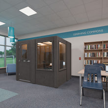 Load image into Gallery viewer, Meeting Booth in a school library under a Learning Commons sign, a windowed meeting pod beside the bookshelves

